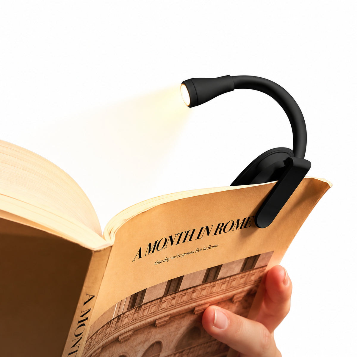 Immerse — clip light on book with hand on white.